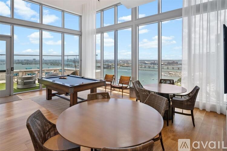 A room with a pool table and a view of the city.