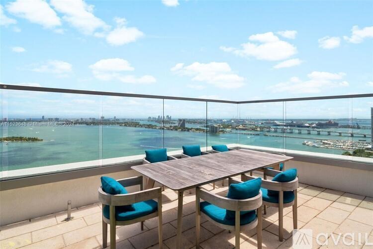 A table with chairs is set up on a balcony overlooking a body of water.