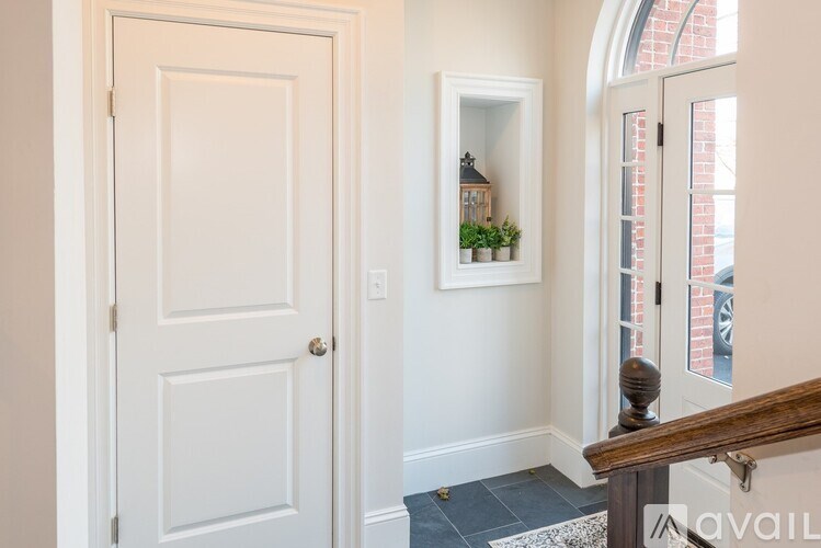 A white door is on the left and a white framed window with plants is on the right.