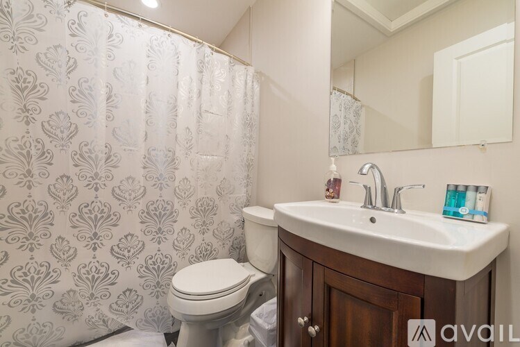 A bathroom with a toilet, sink, and shower curtain.