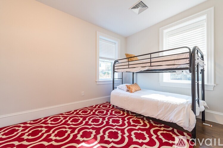A bedroom with a red and white patterned carpet and a metal bunk bed.