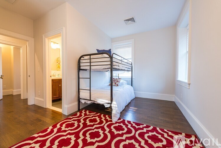 A bedroom with a red and white patterned rug and a metal bunk bed.