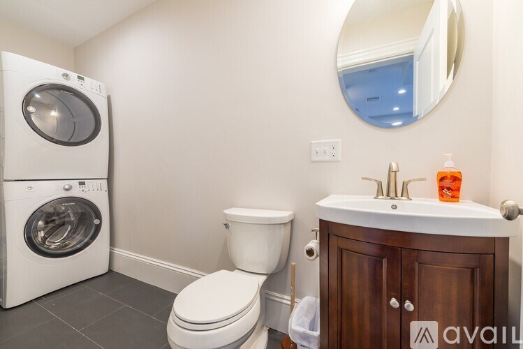 A bathroom with a toilet, sink, and a washer and dryer.