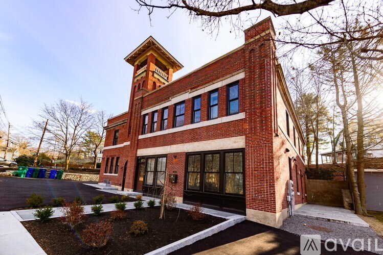A red brick building with a tower and a black door.