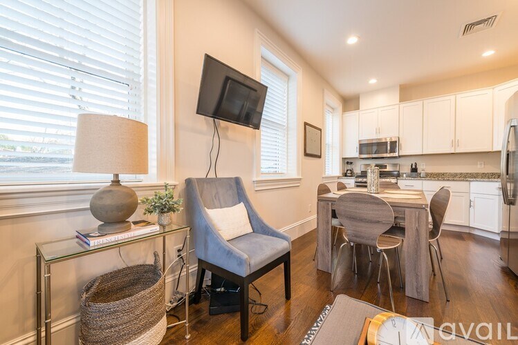 A living room with a grey chair and a glass table with a lamp and a plant on it.