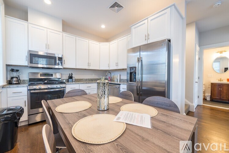A kitchen with a table set for two with a glass of water on it.