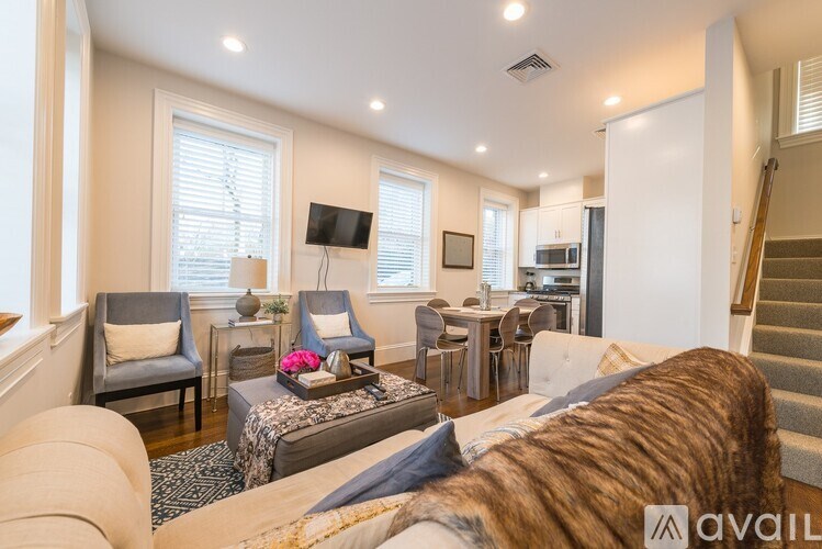 A living room with a couch, chairs, and a television.