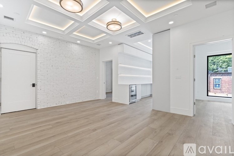 A spacious room with wooden flooring and white walls.