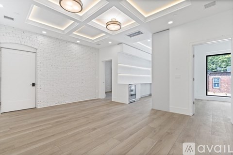 A spacious room with wooden flooring and white walls.