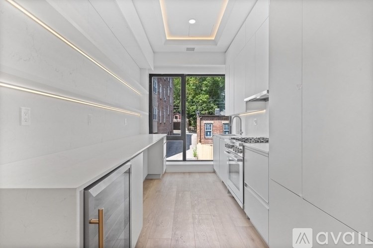 A modern kitchen with white cabinets and a view of a city street outside.