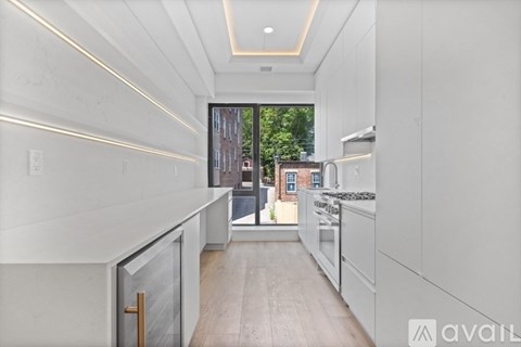 A modern kitchen with white cabinets and a view of a city street outside.