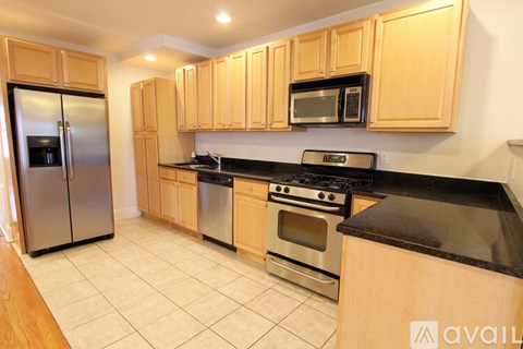 A kitchen with wooden cabinets and black countertops.