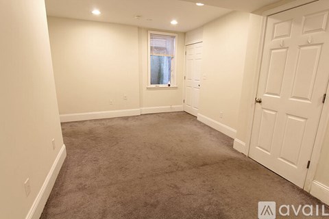 A room with a carpeted floor and a window with a view of a building outside.