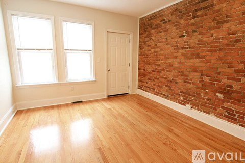 A room with a wooden floor and a brick wall.