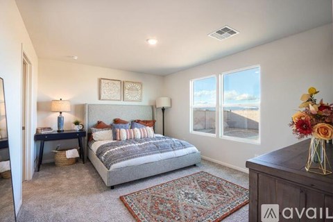 A bedroom with a large bed and a view of the outdoors through the windows.