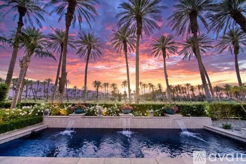 A pool surrounded by palm trees at sunset.