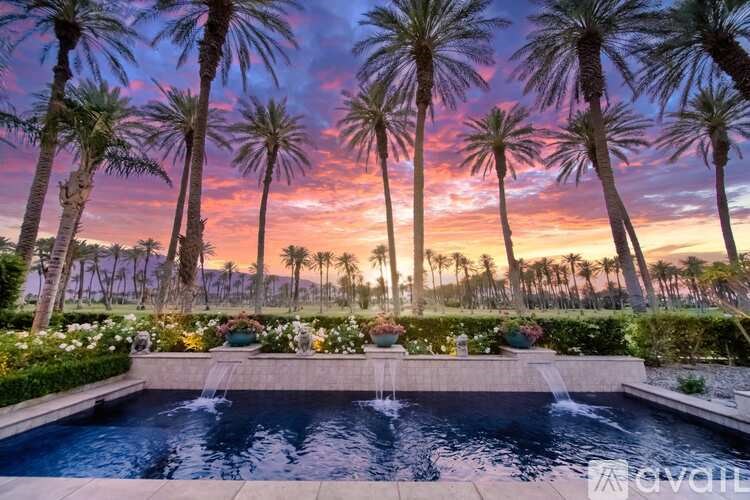 A pool surrounded by palm trees at sunset.