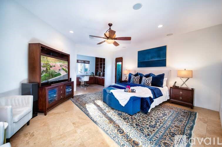 A bedroom with a bed, a couch, and a ceiling fan.