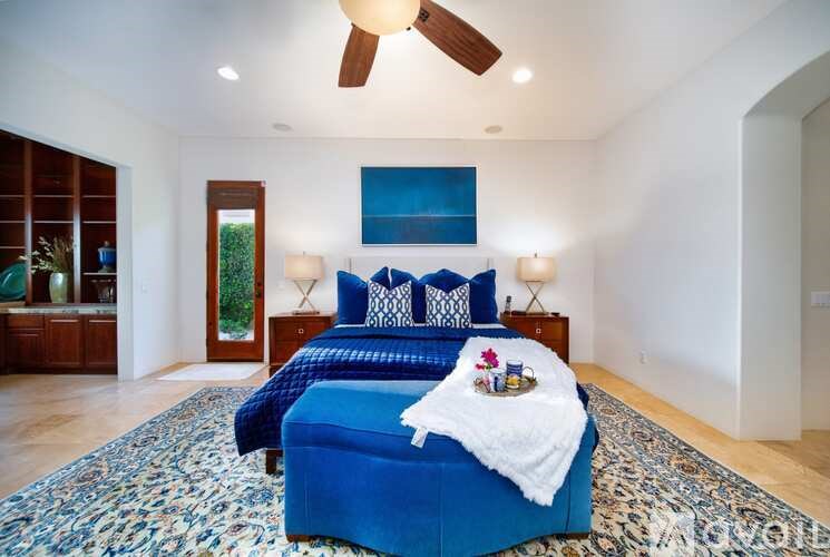 A bedroom with a blue bed and a ceiling fan.