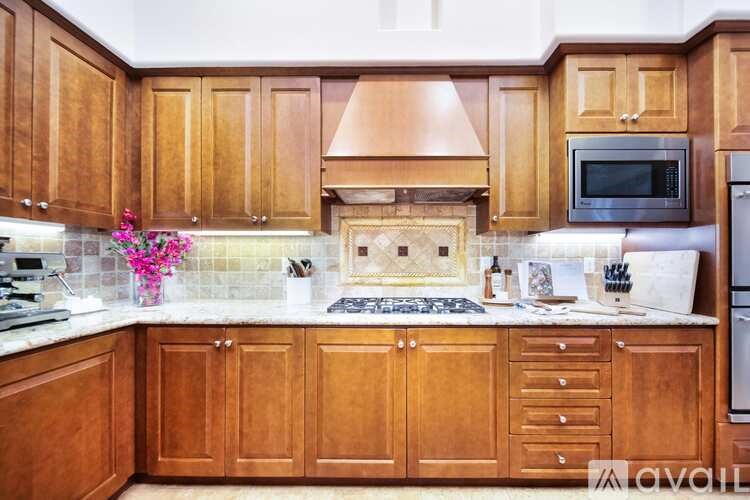 A kitchen with wooden cabinets and a marble countertop.