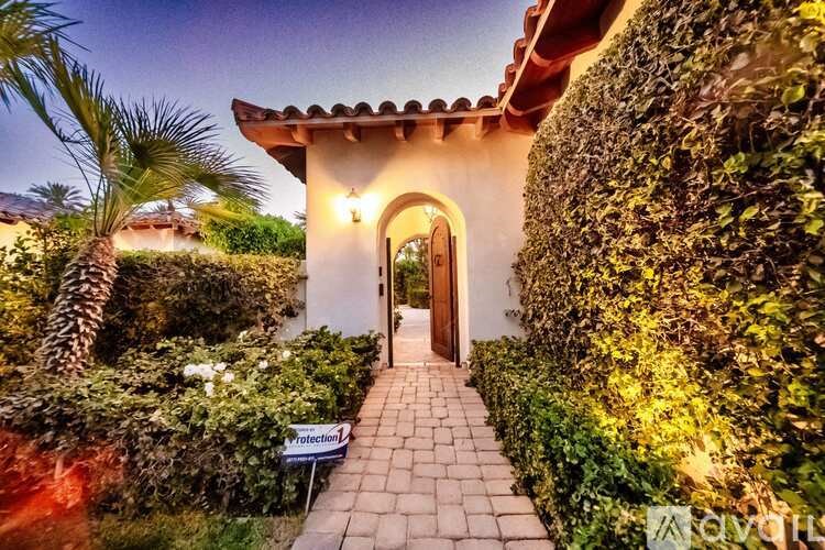 A house with a pathway leading to a door with a sign on the side.
