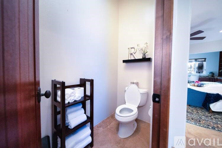 A white toilet is in a small bathroom with a towel rack and a mirror.