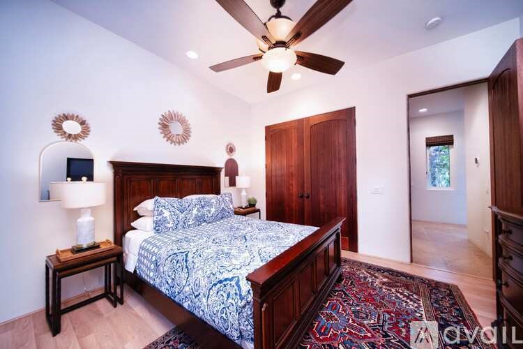 A bedroom with a bed, a ceiling fan, and a rug.