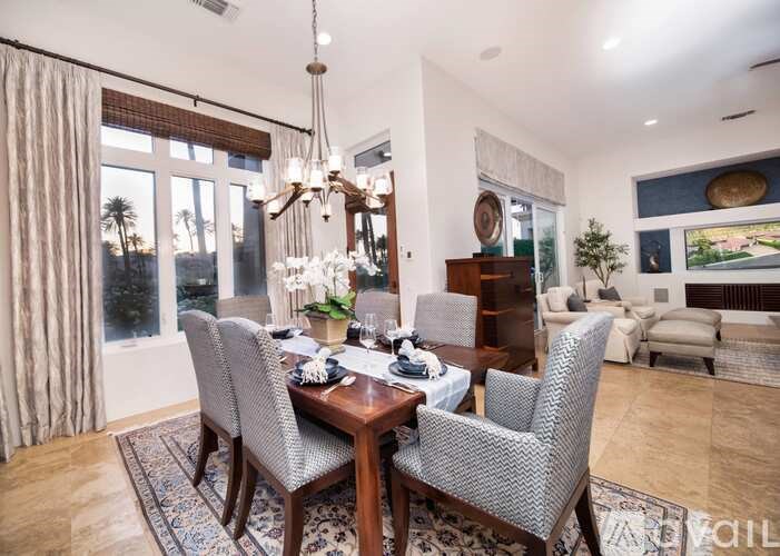 A dining room with a table set for two and a chandelier hanging from the ceiling.