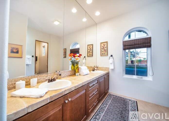 A bathroom with a large mirror, a sink, and a window.