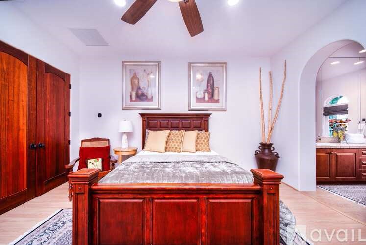 A bedroom with a large bed and a ceiling fan.