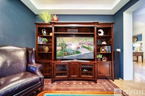 A living room with a brown leather couch and a wooden entertainment center.