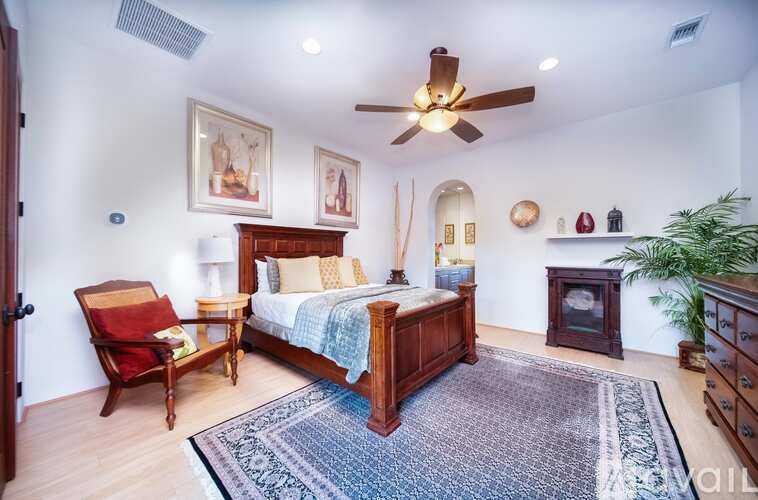 A bedroom with a bed, chair, and fireplace.