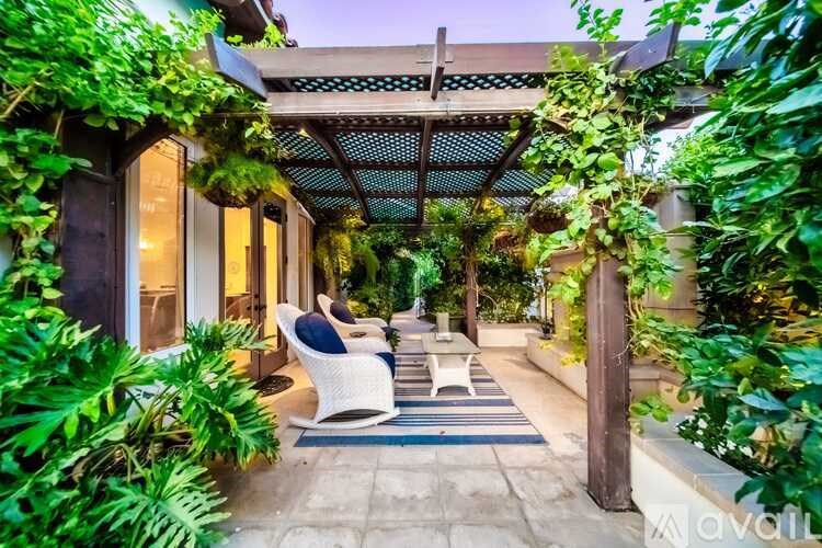 A patio with a white chair and a blue rug.