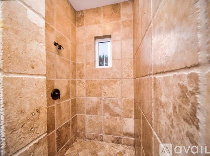 A bathroom with beige tiles and a window.