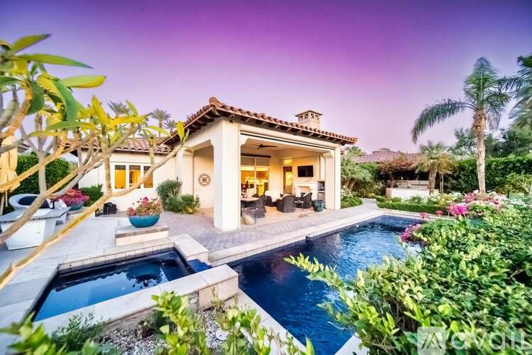 A house with a pool in the foreground and a palm tree to the right.