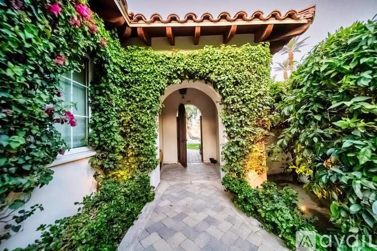 A pathway leads to a doorway covered in greenery.