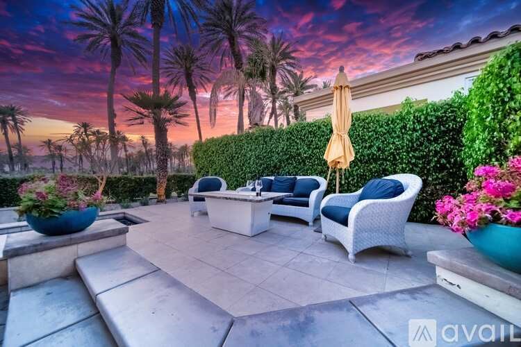 A patio with a table, chairs, and plants is set up for an evening outside.