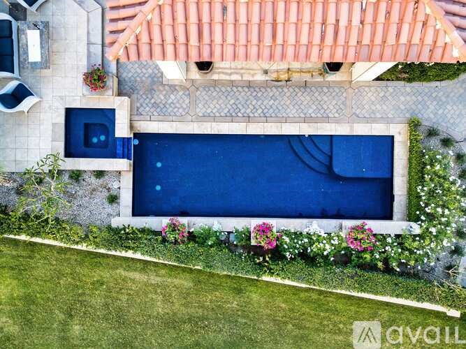 A small pool surrounded by a white fence and pink flowers.