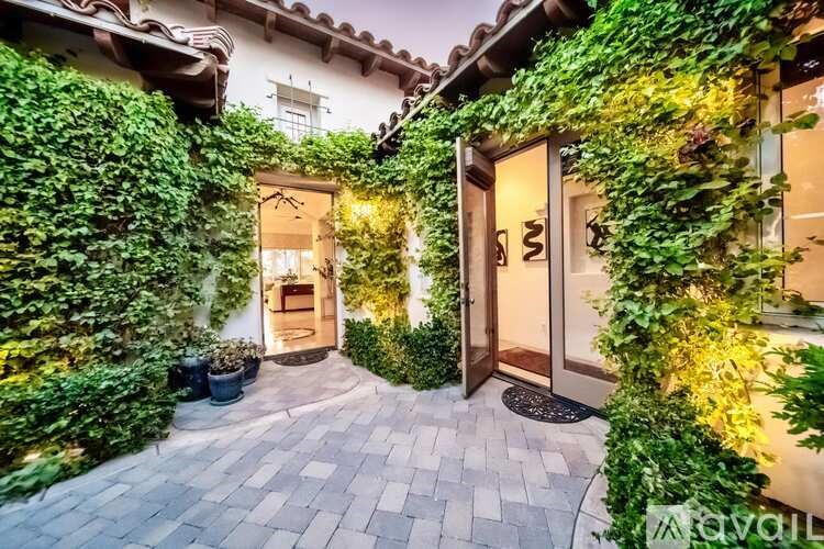 A house entrance with a door and windows covered in greenery.