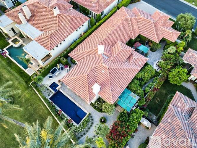 A large house with a red tiled roof and a pool.