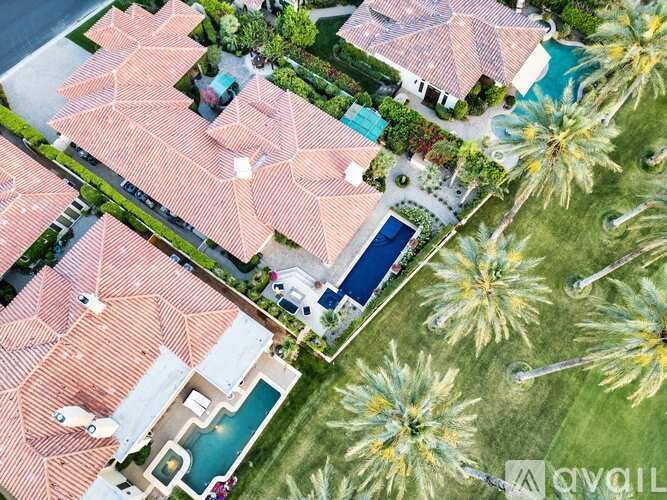 A large house with a pool surrounded by palm trees.