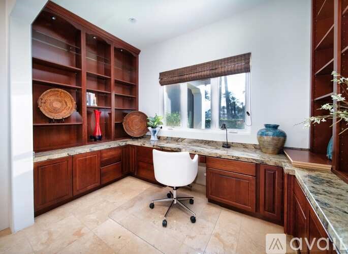 A kitchen with wooden cabinets and a white chair.