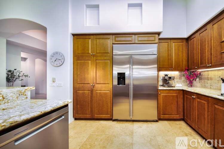 A kitchen with a marble countertop and a stainless steel refrigerator.