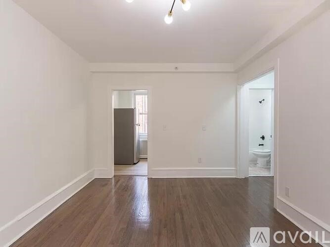 A room with wooden floors and white walls, with a door on the right side.