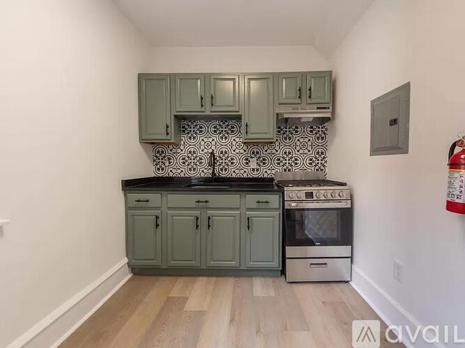 A kitchen with green cabinets and a black countertop.