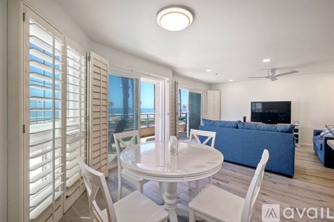 A modern living room with a white dining table and chairs, a blue sofa, and a television.