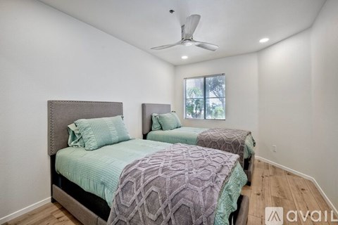 A bedroom with two beds and a ceiling fan.