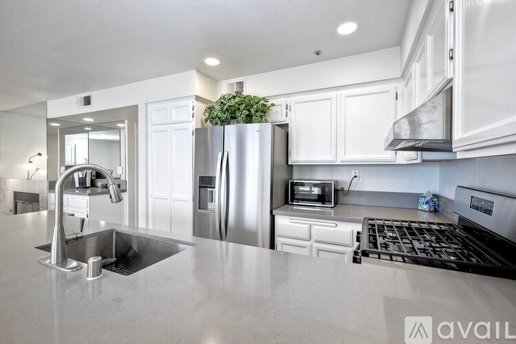 A modern kitchen with a stainless steel refrigerator and a plant on top.