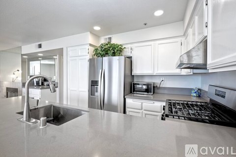 A modern kitchen with a stainless steel refrigerator and a plant on top.