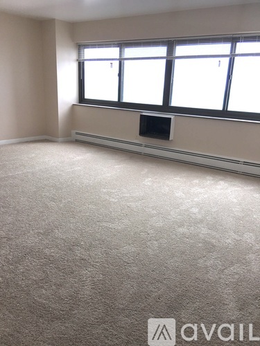 A room with a carpeted floor and a window with blinds.